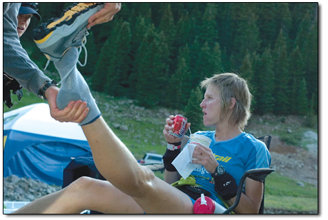 
  Emily Baer fuels her body at the Grouse Gulch aid station while her husband, Ernst, takes care of the foot
  maintenance.
